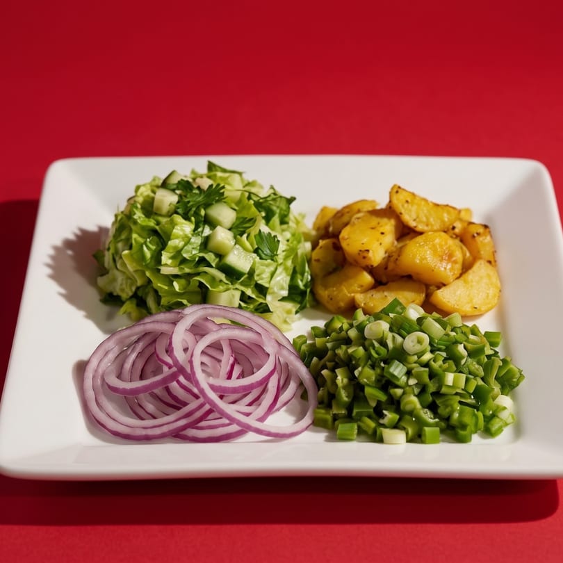 A white plate with four sections of ingredients: lettuce, roasted potatoes, red onion, and green onions.